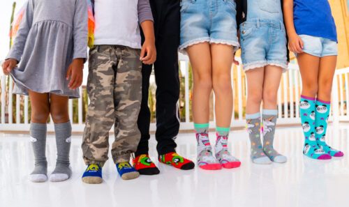 six kids wearing colorful socks on sock skating rink